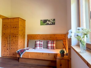 Ein gemütliches Zimmer mit einem hölzernen Bett, einem Kleiderschrank und einem Fenster mit Blumen.