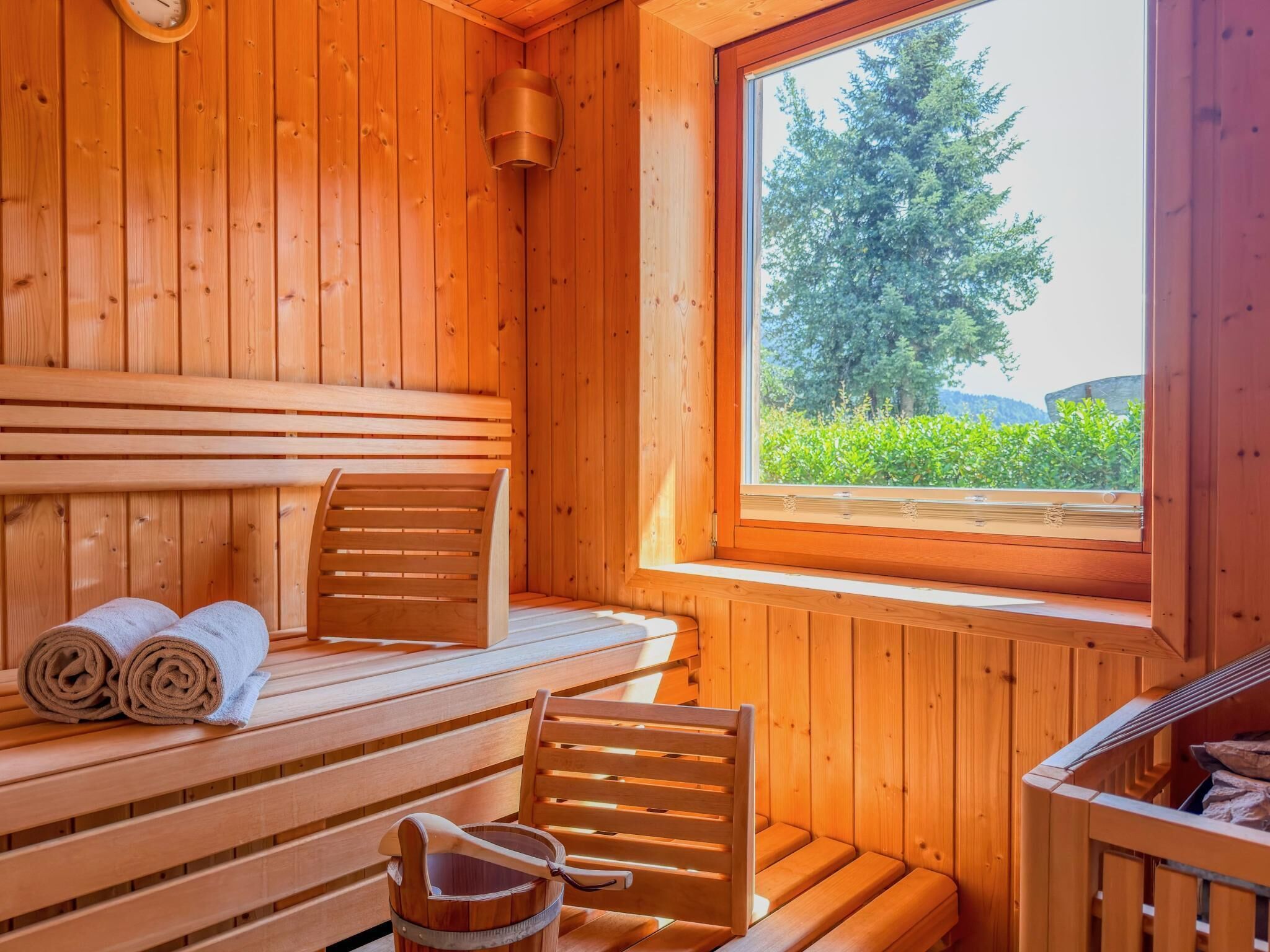 Een sauna met houten banken, een raam met uitzicht op groen en een handdoek op de bank.