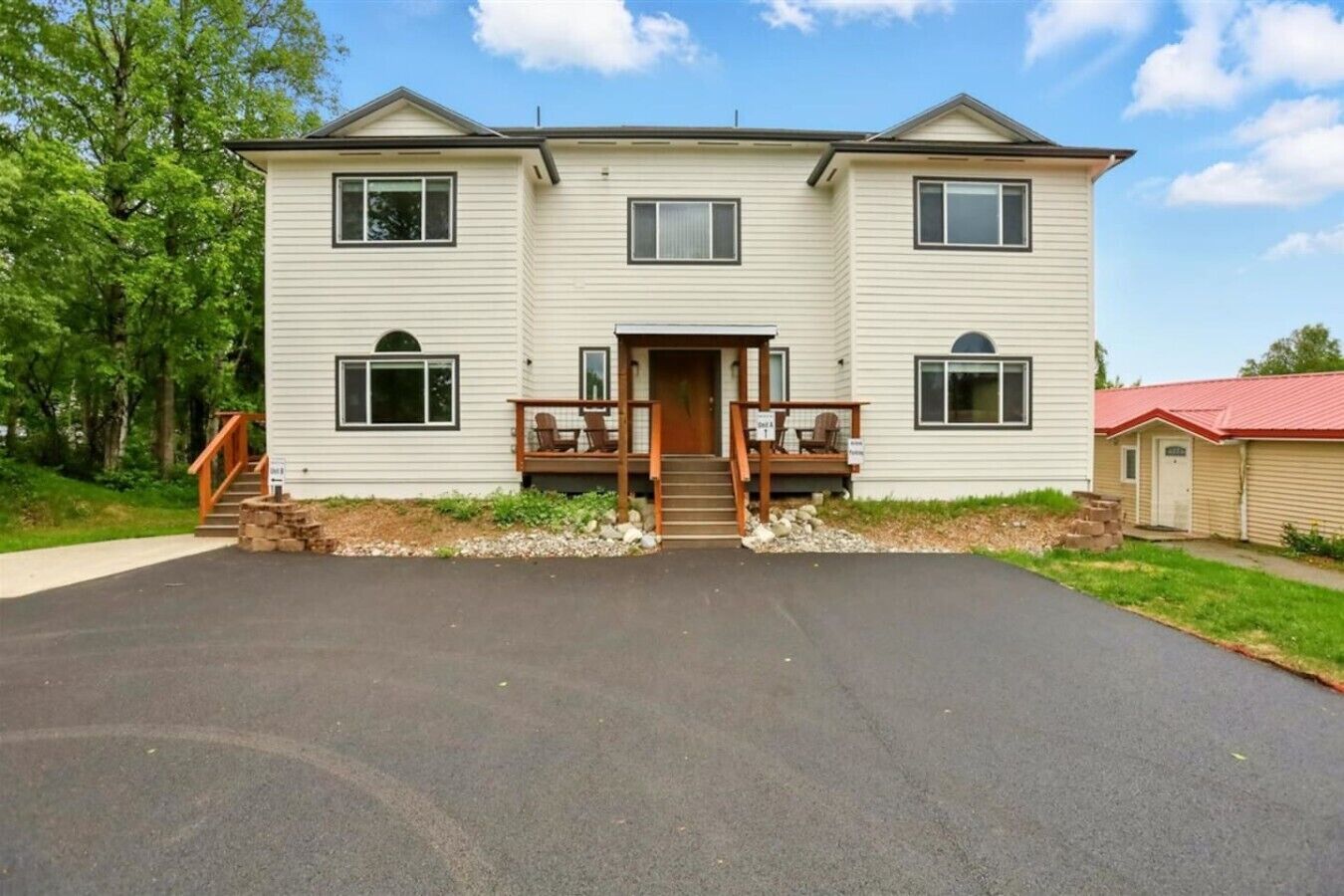 A two-story house with a front porch, a staircase leading to the entrance, and a driveway.