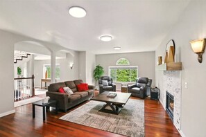 Ein geräumiges Wohnzimmer mit einem braunen Sofa, zwei Ledersesseln, einem Couchtisch und einem Kamin.