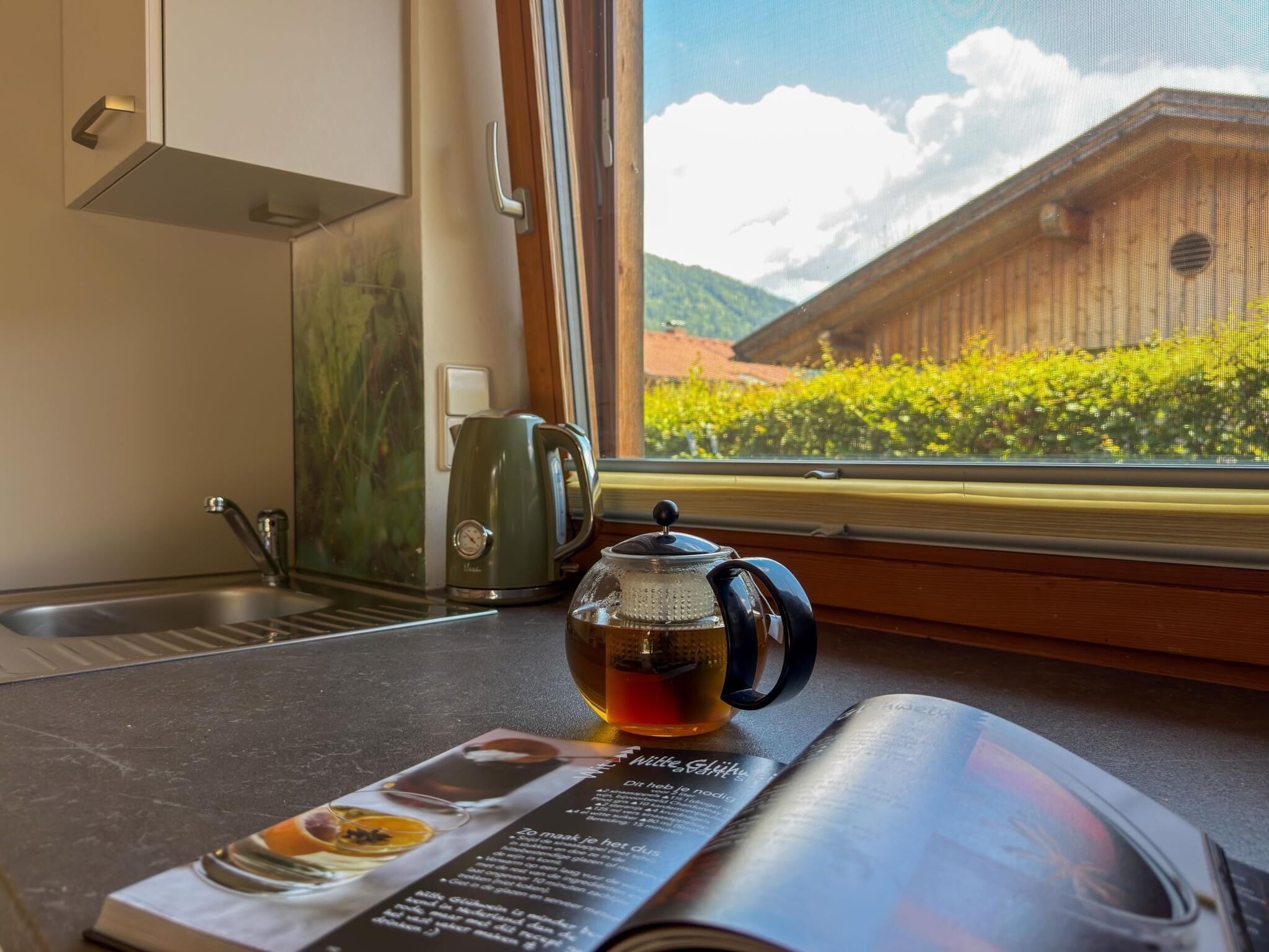 Eine Küche mit Fensterblick, einem Wasserkocher und einer Speisekarte.