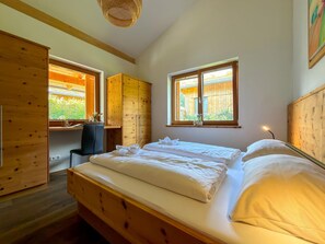 Une chambre à coucher avec un lit en bois, un bureau et une fenêtre donnant sur un paysage verdoyant.