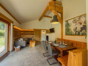 A spacious room with a wooden ceiling, a dining area with a table set for four, and a cozy seating area with a sofa and chairs. - Chalet with sauna and garden near Pressegger See (Hermagor-Pressegger See)