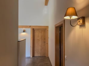 A hallway with a wooden door at the end, a wall-mounted lamp, and a small shelf. - Chalet with sauna and garden near Pressegger See (Hermagor-Pressegger See)