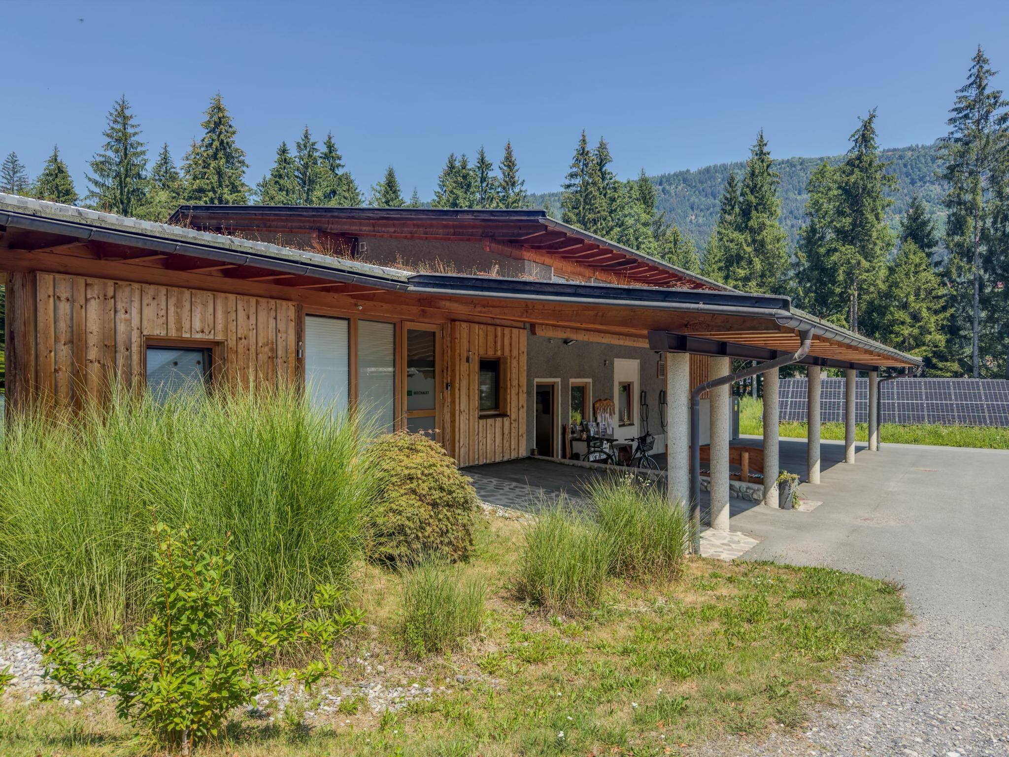 Eine Holzhütte mit Veranda, umgeben von Grün und mit Blick auf Berge.