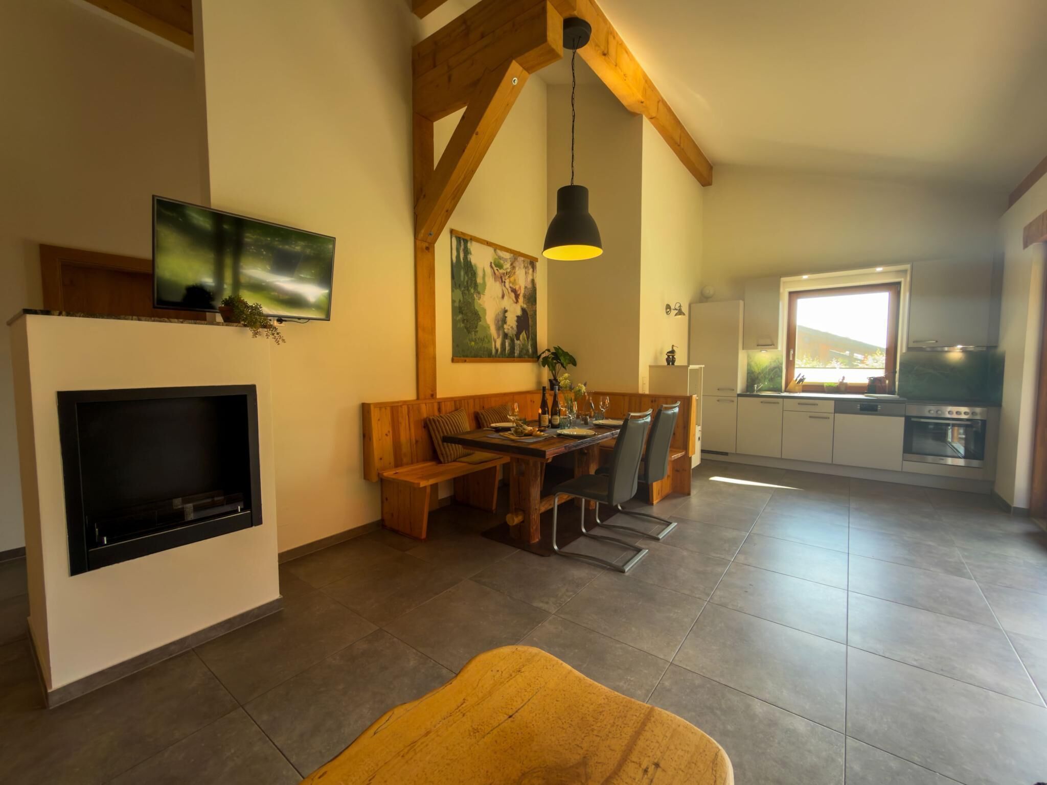 Una cocina moderna con zona de comedor, chimenea y ventana grande.