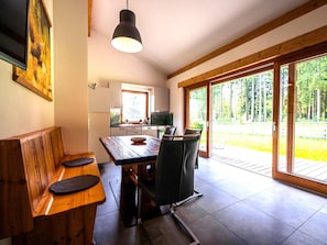 Eine moderne Küche mit Essbereich, einer Holzbank und einer großen Schiebeglastür zu einer Terrasse.