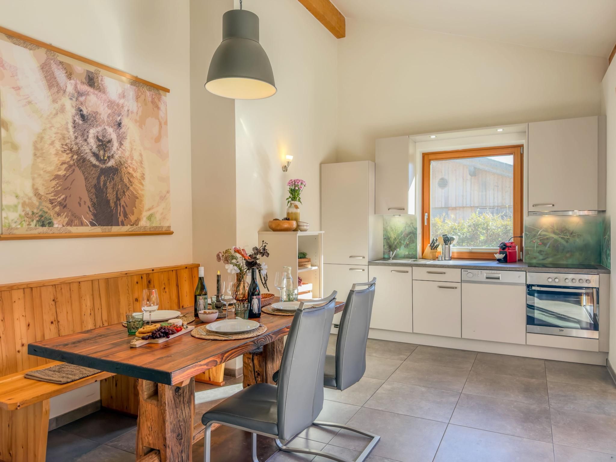 A modern kitchen with white cabinets, a built-in oven, and a large window.