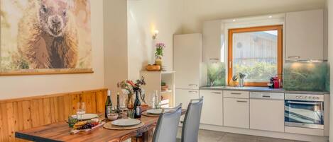 A modern kitchen with white cabinets, a built-in oven, and a large window.
