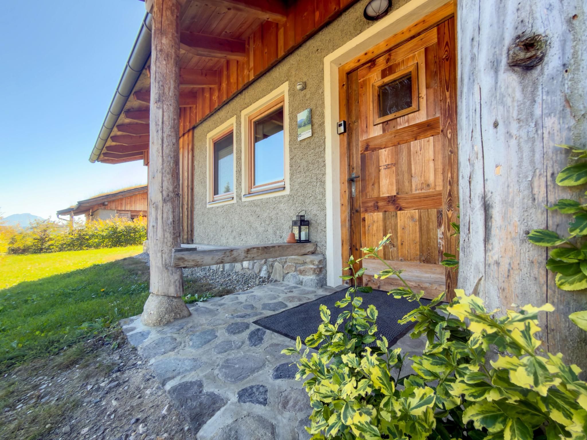A rustic cabin with a stone foundation, wooden exterior, and a welcoming entrance with a bench.