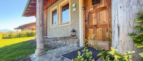 A rustic cabin with a stone foundation, wooden exterior, and a welcoming entrance with a bench.