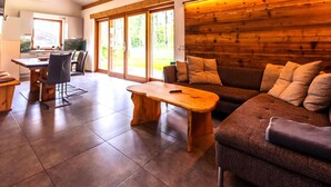 Amplia sala de estar con una pared de madera, un sofá, una mesa de centro y una mesa de comedor con sillas.