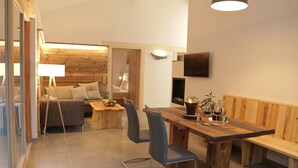 Un interior acogedor con una mesa de comedor de madera, un sofá y un televisor montado en la pared.