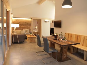 Ein gemütliches Interieur mit einem Holzesstisch, einer Couch und einem an der Wand befestigten Fernseher.