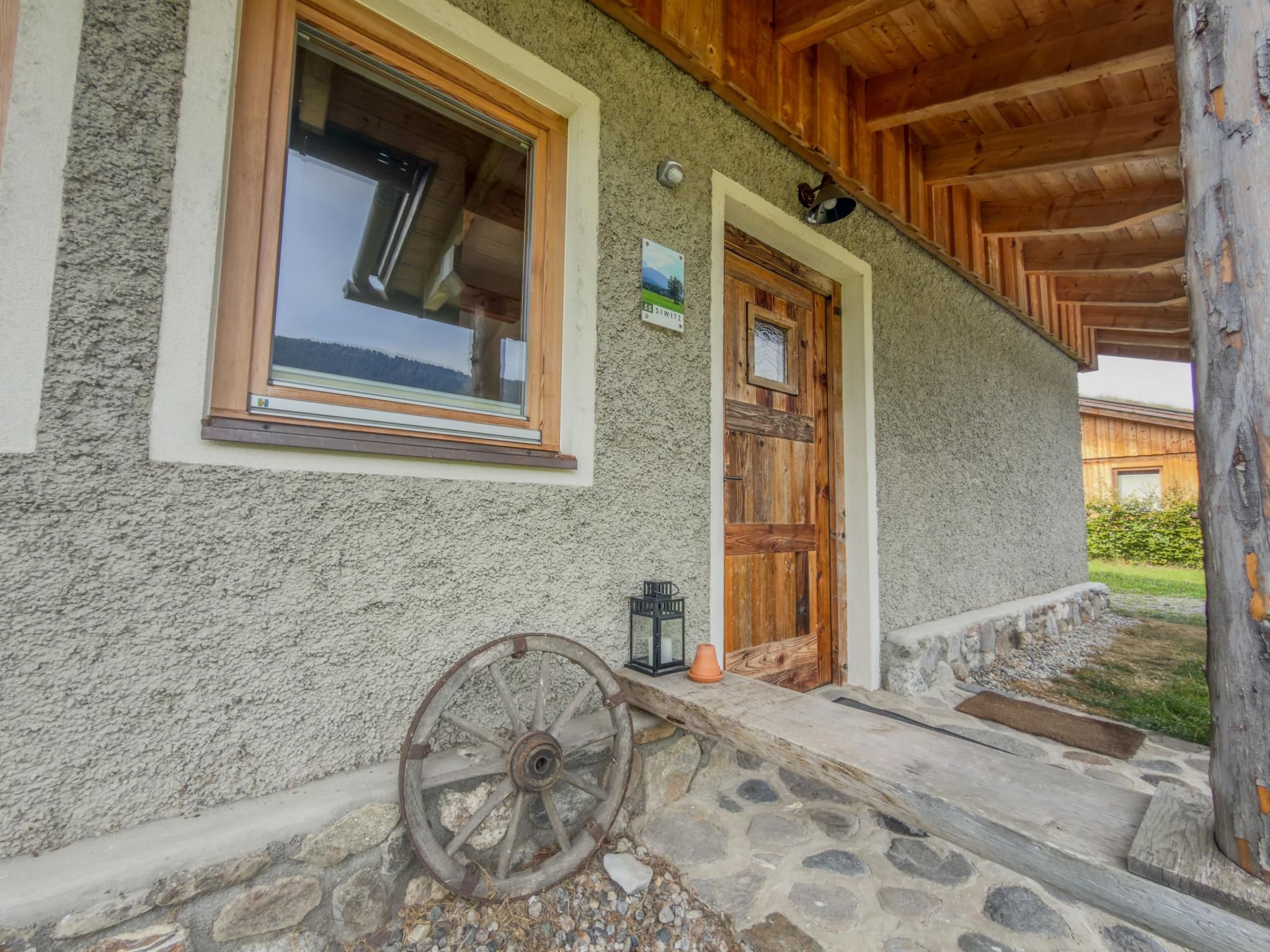 A rustic building with a stone facade, wooden doors, and a large window.