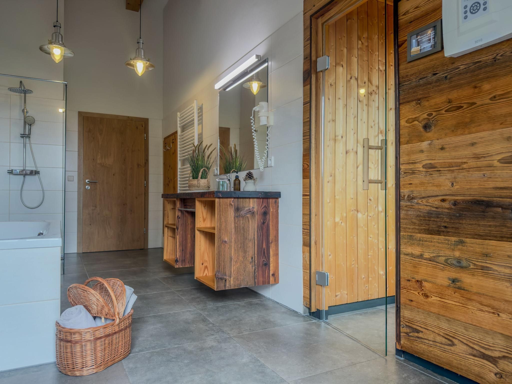 Ein modernes Badezimmer mit einem Holz-Waschtisch, einer Dusche und einem großen Spiegel.