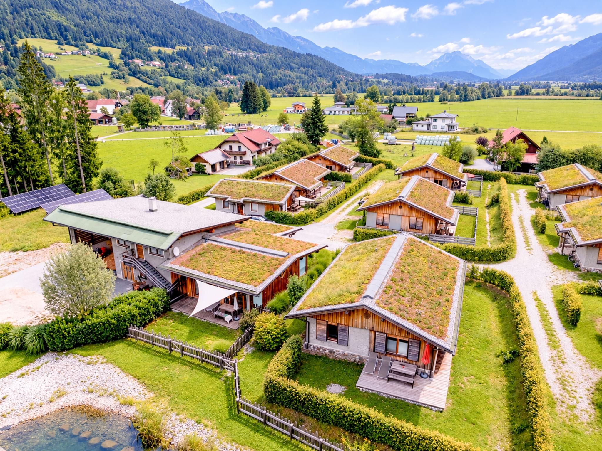 Un ensemble de maisons aux toits verts, entourées d’une végétation luxuriante et dominant un paysage montagneux.