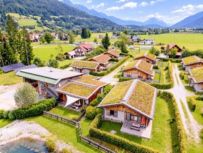 Un ensemble de maisons aux toits verts, entourées d’une végétation luxuriante et dominant un paysage montagneux.