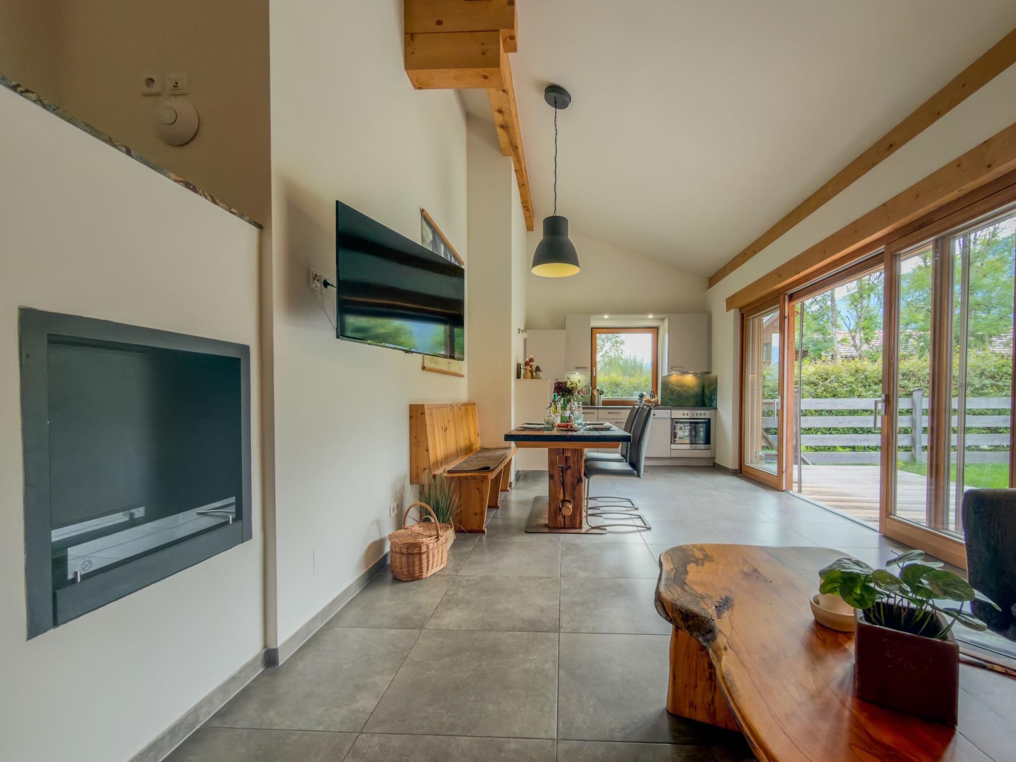 A spacious living area with a large flat-screen TV, wooden furniture, and a dining table.