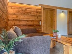 Une pièce chaleureuse avec un mur en bois, un canapé, une table en bois et une porte.