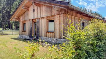 Eine Holzhütte mit steinernen Fundamenten, großen Fenstern und einem geneigten Dach.
