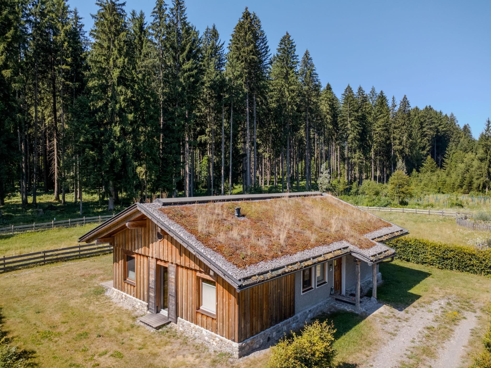 Eine Holzhütte mit geneigtem Dach, umgeben von einem Wald.
