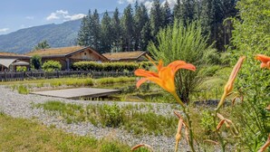 A lakeside hotel with wooden cabins, a dock, and a forested mountain backdrop.