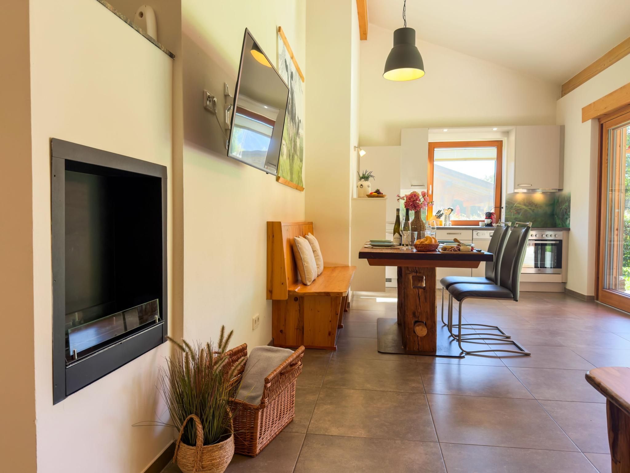 Een moderne keuken met een eethoek, een tv aan de muur en een groot raam dat voor natuurlijk licht zorgt.