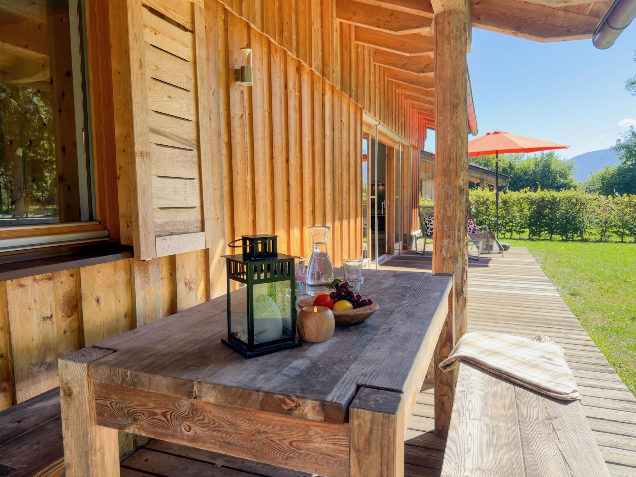 Une terrasse en bois avec une table dressée pour le repas, une lanterne et une bougie.