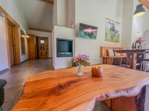 A spacious living area with a large wooden table, a flat-screen TV mounted on the wall, and a cozy seating arrangement.