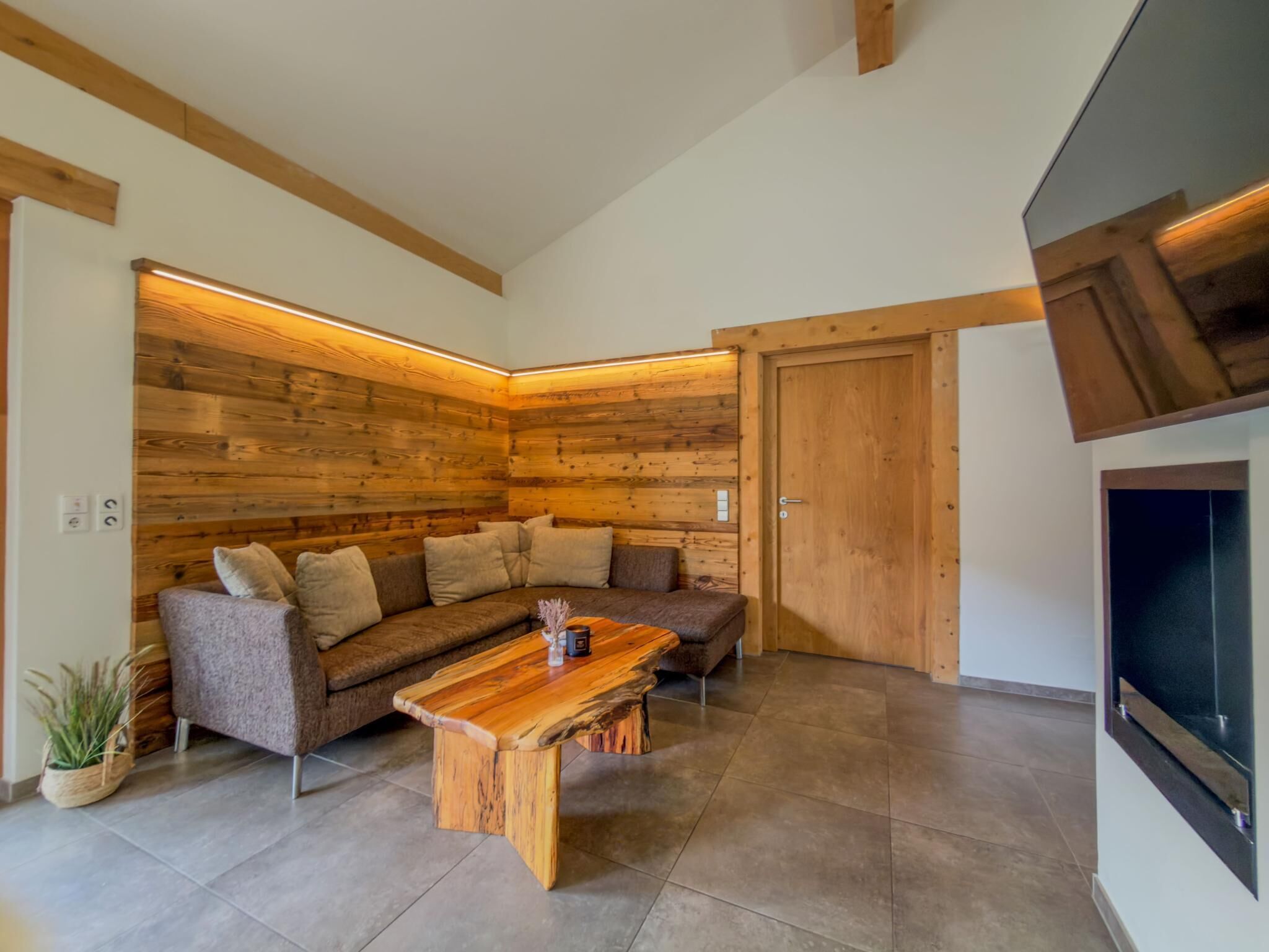 A modern living room with a wooden accent wall, a sectional sofa, a coffee table, and a fireplace.