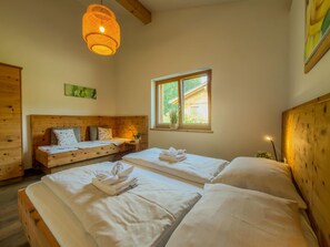 Een kamer met twee bedden, een houten hoofdeinde, een raam met uitzicht en een hanglamp.