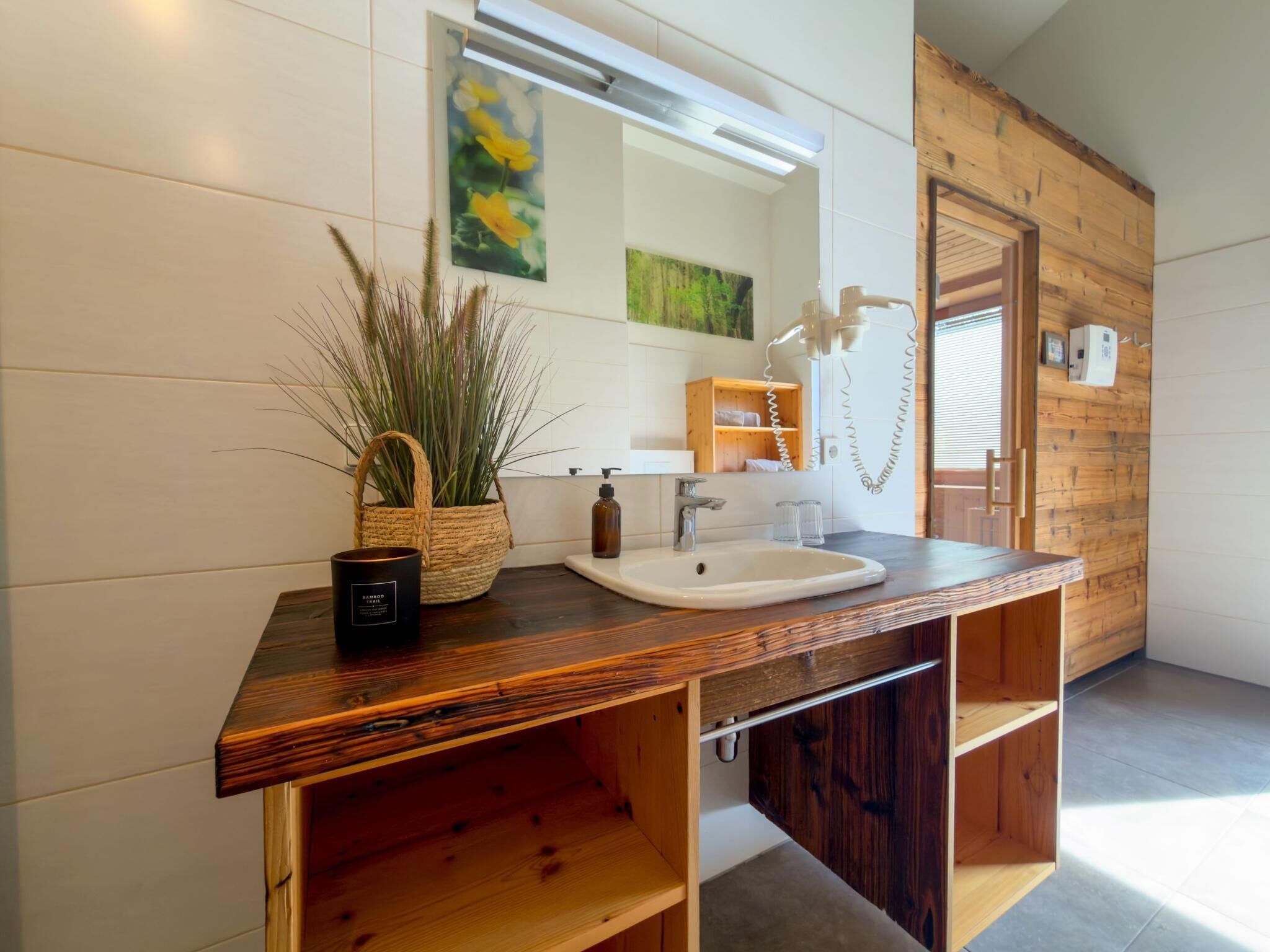A bathroom with a wooden vanity, a sink, a mirror, and a towel rack.