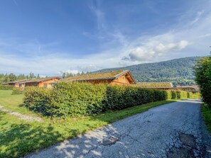 A rural road leading to a row of wooden buildings with a mountain backdrop. - Chalet with sauna near the Nassfeld region (Hermagor-Pressegger See)