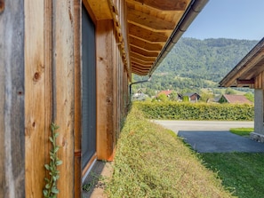 A wooden building with a sloped roof and a view of a green landscape with houses in the distance.