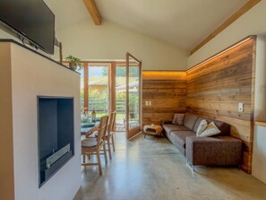 A modern living room with a fireplace, a sofa, and a dining area with chairs.