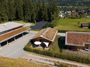 A modern building with a sloped roof, solar panels, and a covered outdoor seating area.