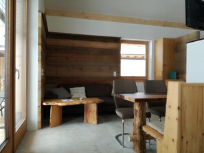 Une piĂšce confortable, amĂ©nagĂ©e dans le style dâun chalet, avec un banc en bois, une table Ă manger et un canapĂ©.