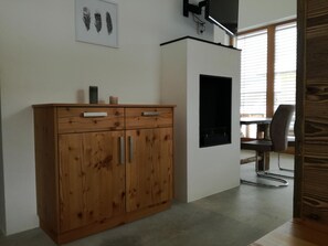 Un meuble en bois avec des tiroirs, un téléviseur à écran plat fixé au mur et une œuvre d’art représentant des plumes, encadrée, qui décore le mur.