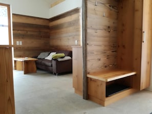 Une piÚce avec un mur en bois, un canapé, une petite table et un banc.