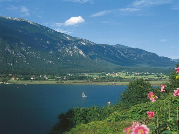 A lake with mountains in the background, a small boat, and some houses near the shore.