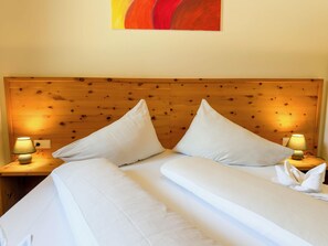 A hotel room with a wooden headboard, two beds with white linens, and two bedside lamps.