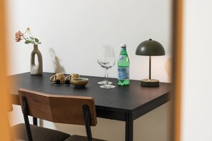 Ein Esstisch mit einer Vase, zwei Weingläsern, einer Wasserflasche, einer Lampe und einem Stuhl.