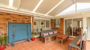 A modern interior with a brick wall, a blue door, a wooden bench, and a table with a colorful cushion.