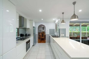 A modern kitchen with white cabinetry, stainless steel appliances, and pendant lighting.