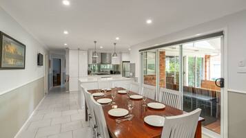 A modern kitchen with white cabinetry, a central island, and a dining area with a wooden table set for six.