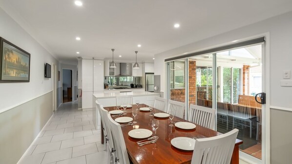 A modern kitchen with white cabinetry, a central island, and a dining area with a wooden table set for six.