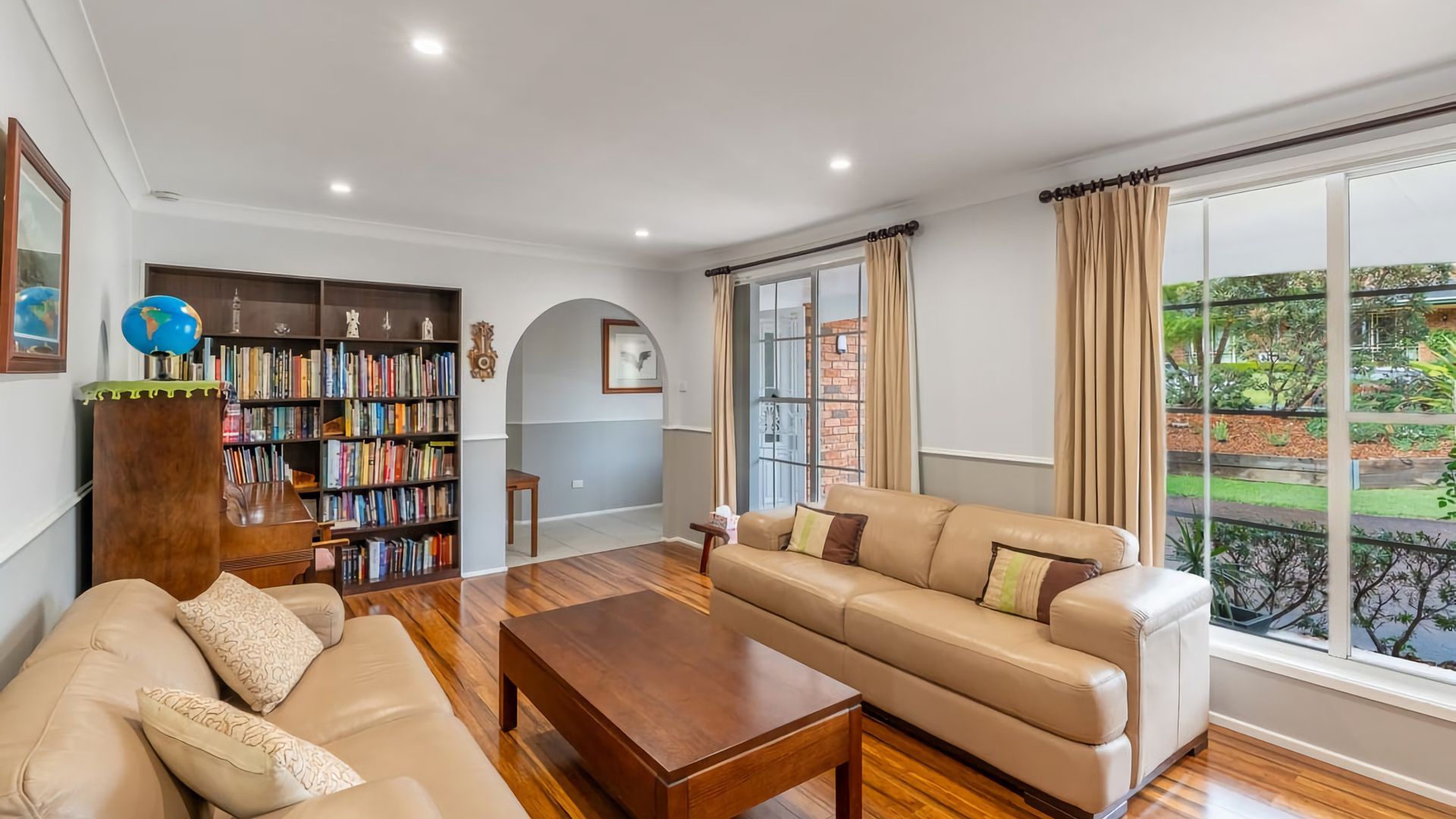 A spacious living room with a sofa, coffee table, and a bookshelf filled with books.