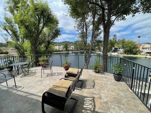 Eine Terrasse mit Sitzgelegenheiten, Blick auf einen See und umliegende Bäume.