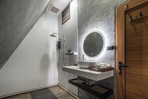 A modern bathroom with a shower, a sink with a mirror, and a wooden door.
